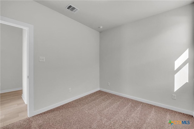 unfurnished room featuring light colored carpet, visible vents, and baseboards