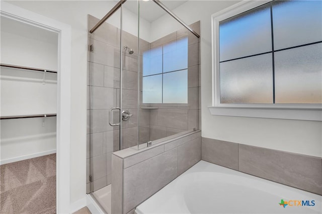 full bath featuring a garden tub, a spacious closet, and a shower stall