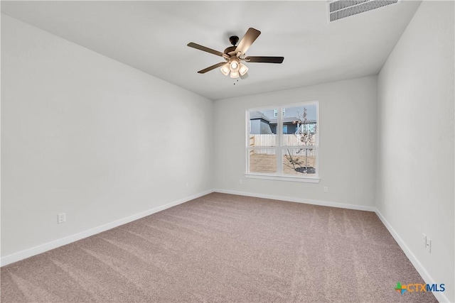 empty room featuring carpet flooring, visible vents, ceiling fan, and baseboards