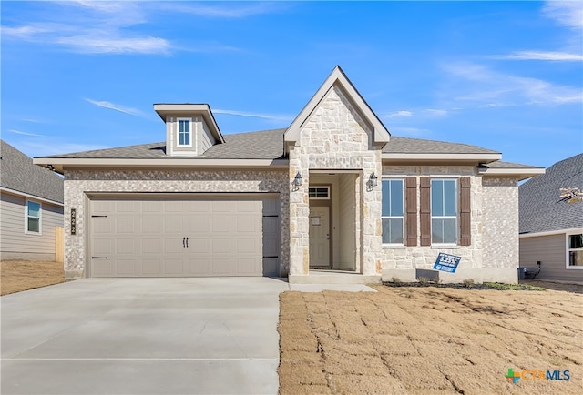 view of front facade with a garage, stone siding, concrete driveway, and roof with shingles