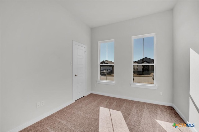 unfurnished room featuring carpet floors and baseboards