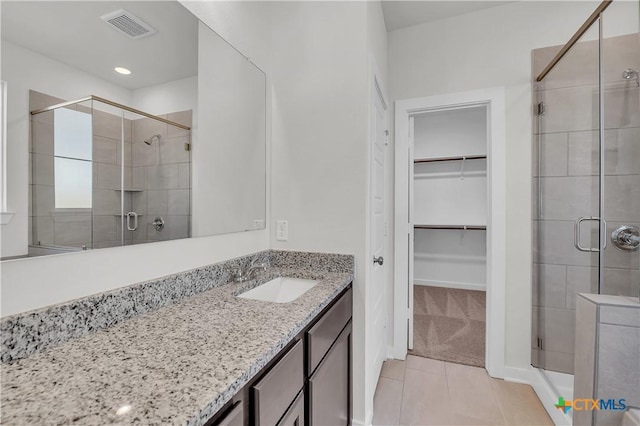 full bath with a walk in closet, visible vents, vanity, a shower stall, and tile patterned flooring