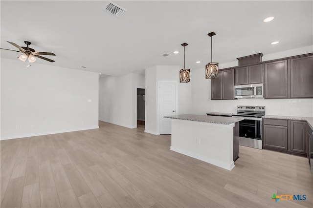 kitchen with stainless steel appliances, a center island, open floor plan, and decorative light fixtures