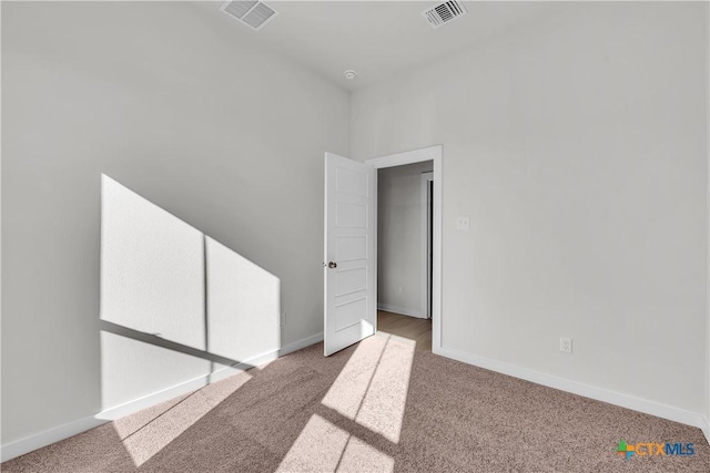 unfurnished room with visible vents, light carpet, and baseboards