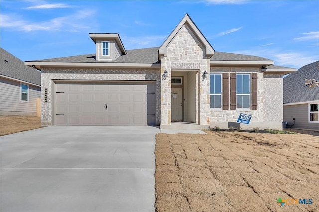 view of front facade with stone siding, an attached garage, and driveway