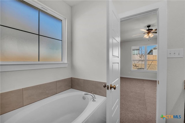 bathroom featuring ceiling fan, baseboards, and a bath