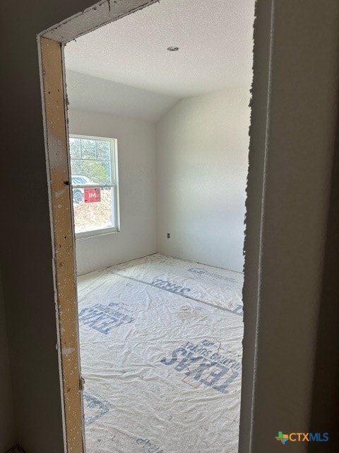 empty room with a textured ceiling and vaulted ceiling