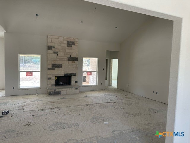 unfurnished living room with a fireplace, a wealth of natural light, and lofted ceiling