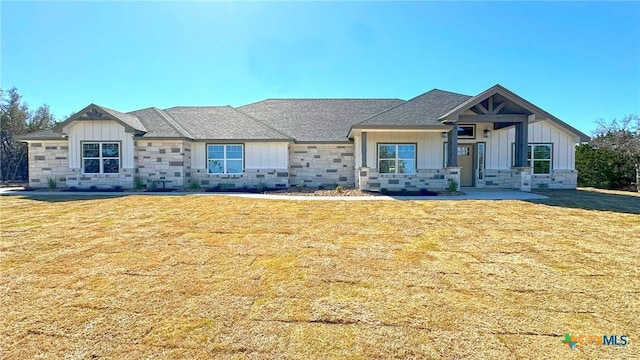 view of front facade featuring stone siding, board and batten siding, and a front yard