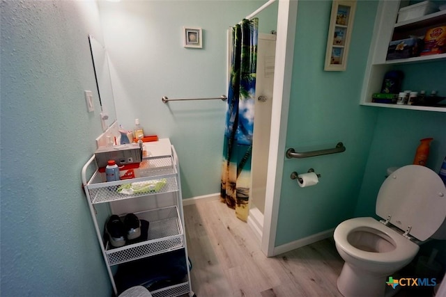 bathroom featuring a shower with shower curtain, hardwood / wood-style flooring, and toilet