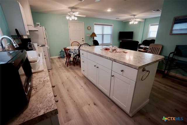 kitchen featuring ceiling fan, a center island, light hardwood / wood-style floors, white cabinets, and exhaust hood