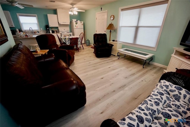 living room featuring ceiling fan, sink, and light hardwood / wood-style floors