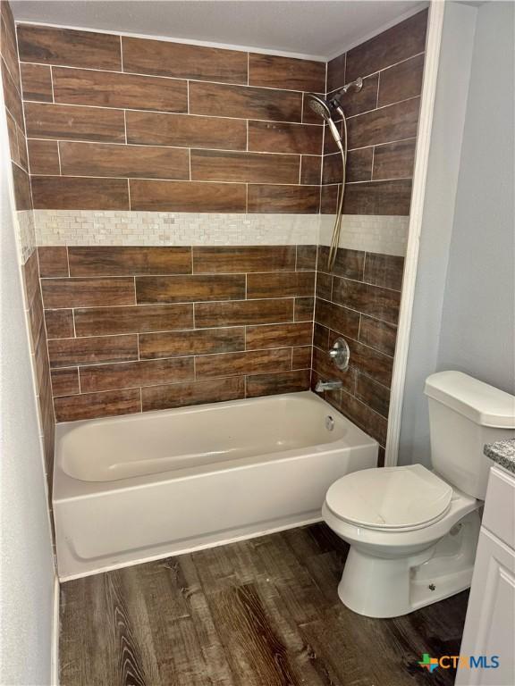 full bath featuring vanity,  shower combination, wood finished floors, and toilet