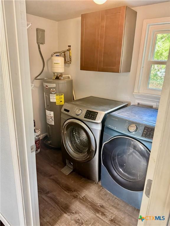 laundry area featuring dark wood-type flooring, cabinet space, independent washer and dryer, and electric water heater