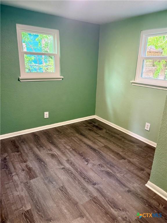 empty room featuring baseboards and dark wood-style floors
