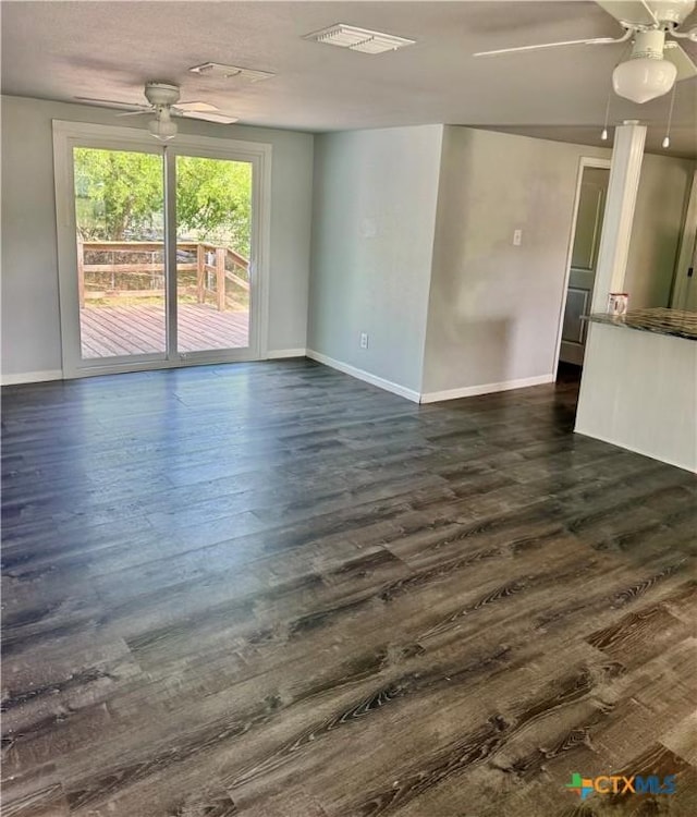 empty room featuring baseboards, a ceiling fan, and dark wood-style floors