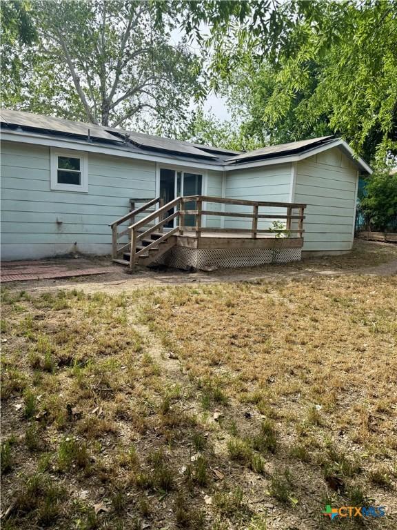 view of front facade featuring a wooden deck and a front lawn