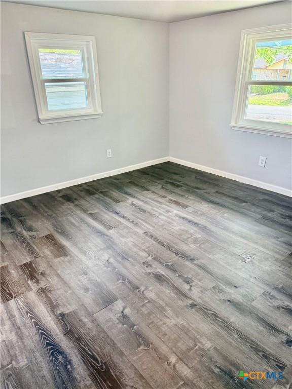 spare room with baseboards and wood finished floors