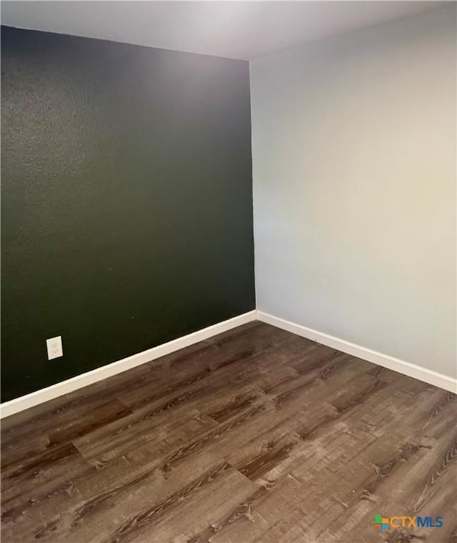 empty room featuring dark wood-type flooring and baseboards