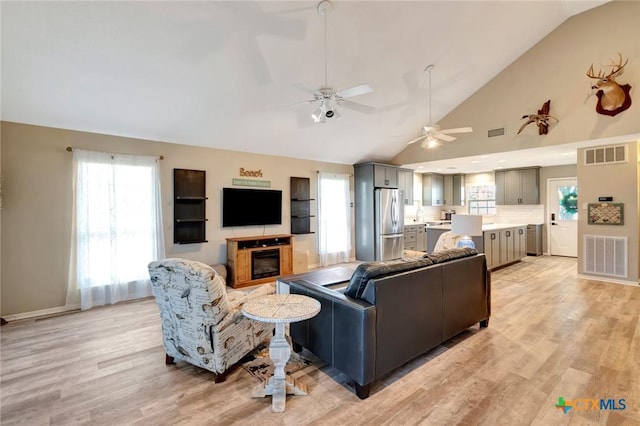 612 W Jackson Ave, Port Oconnor, TX 77982 - living room with vaulted ceiling, ceiling fan, light wood finished floors, plenty of natural light, and a glass covered fireplace