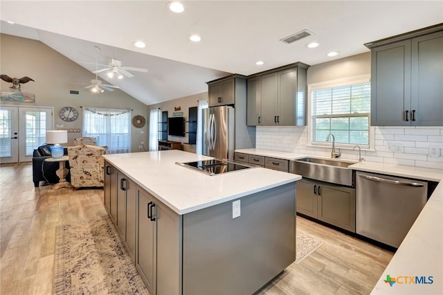 612 W Jackson Ave, Port Oconnor, TX 77982 - kitchen with stainless steel appliances, a sink, light wood finished floors, ceiling fan, and backsplash