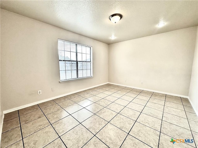 tiled empty room with a textured ceiling