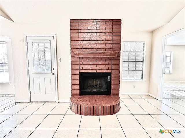 unfurnished living room with tile patterned flooring and a brick fireplace