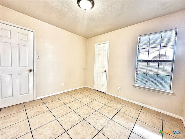 tiled empty room featuring a textured ceiling