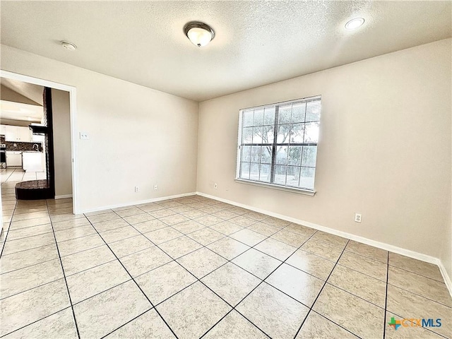 spare room with light tile patterned floors and a textured ceiling