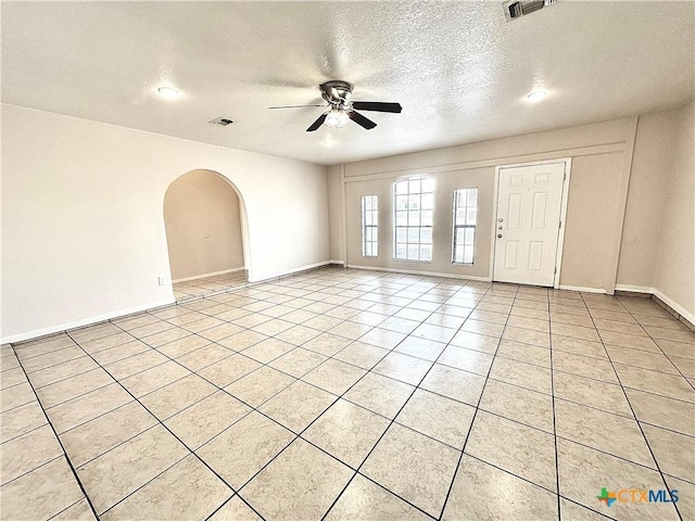 spare room featuring a textured ceiling, ceiling fan, and light tile patterned flooring