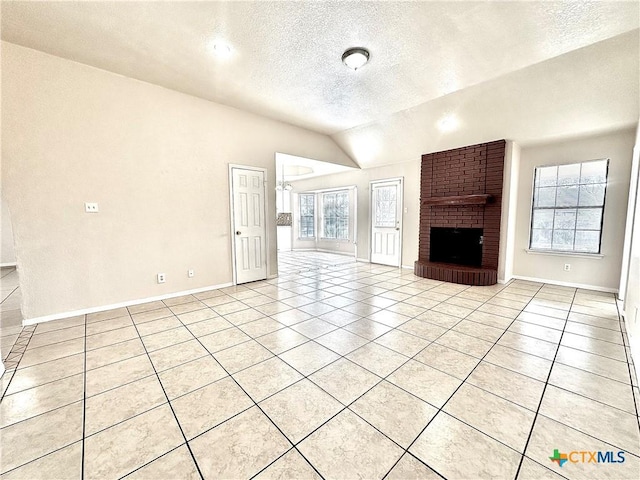 unfurnished living room with light tile patterned flooring, lofted ceiling, a textured ceiling, and a brick fireplace