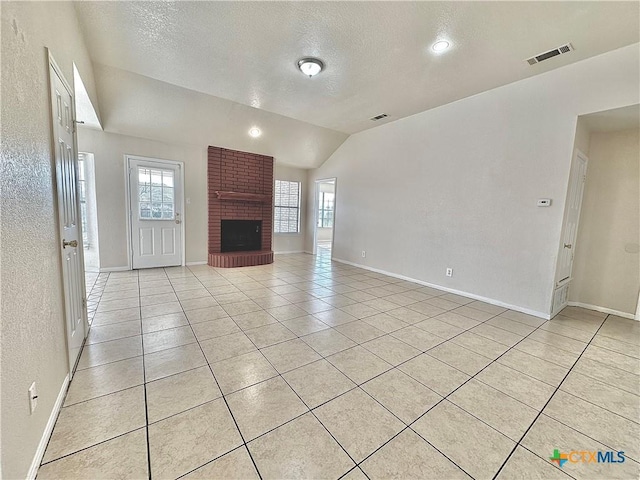 unfurnished living room featuring a brick fireplace, light tile patterned floors, a textured ceiling, and vaulted ceiling