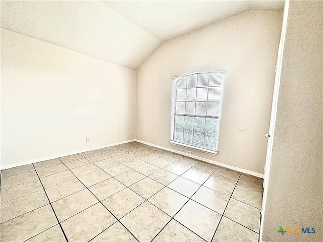 spare room with light tile patterned floors and lofted ceiling