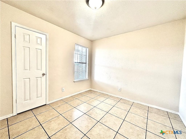 empty room with light tile patterned floors and a textured ceiling