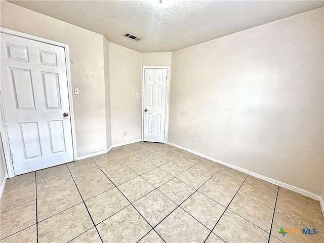 empty room featuring tile patterned flooring and a textured ceiling