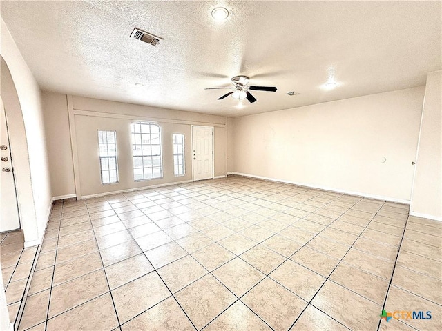 tiled empty room with ceiling fan and a textured ceiling