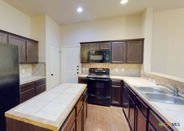 kitchen with sink, black appliances, dark brown cabinets, a center island, and decorative backsplash