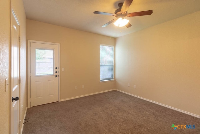 empty room with ceiling fan and dark colored carpet