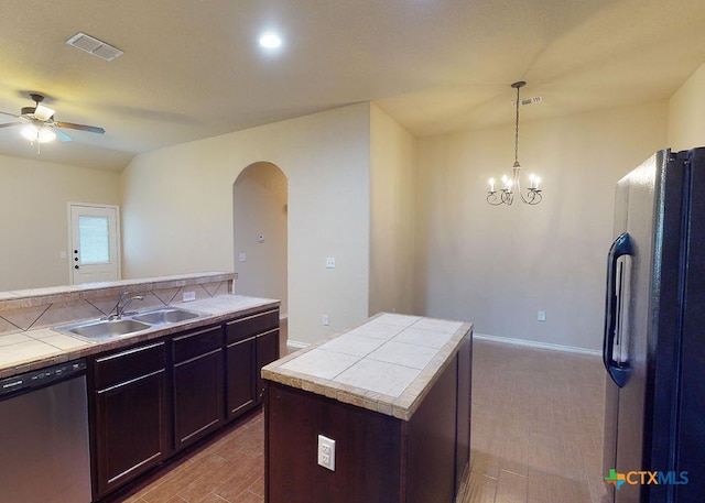 kitchen featuring sink, stainless steel dishwasher, hanging light fixtures, a center island, and black refrigerator