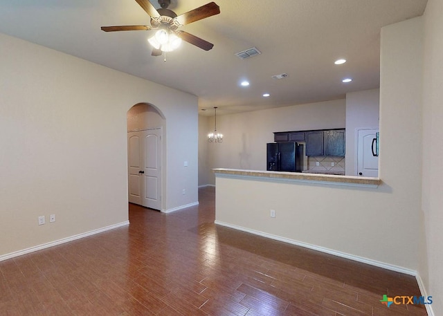 unfurnished living room with dark wood-type flooring and ceiling fan with notable chandelier