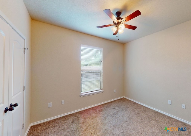 empty room with a textured ceiling, light colored carpet, and ceiling fan