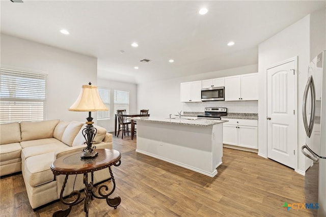 837 Margay Loop, Seguin, TX 78155 - kitchen with appliances with stainless steel finishes, open floor plan, tasteful backsplash, white cabinetry, and light wood-style flooring