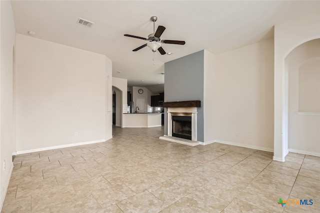 unfurnished living room featuring ceiling fan, sink, and light tile patterned floors