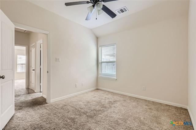 unfurnished room featuring lofted ceiling, a wealth of natural light, and carpet