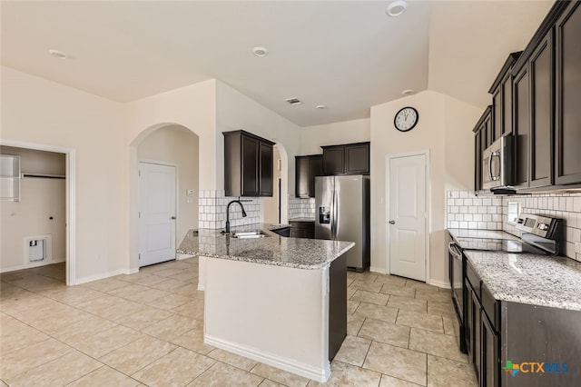 kitchen with decorative backsplash, light stone countertops, appliances with stainless steel finishes, and sink