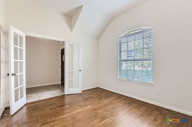 spare room featuring french doors, hardwood / wood-style flooring, and vaulted ceiling