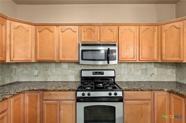 kitchen featuring appliances with stainless steel finishes, decorative backsplash, and dark stone countertops