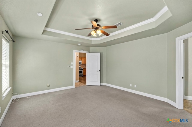 unfurnished bedroom with crown molding, carpet flooring, ceiling fan, and a tray ceiling