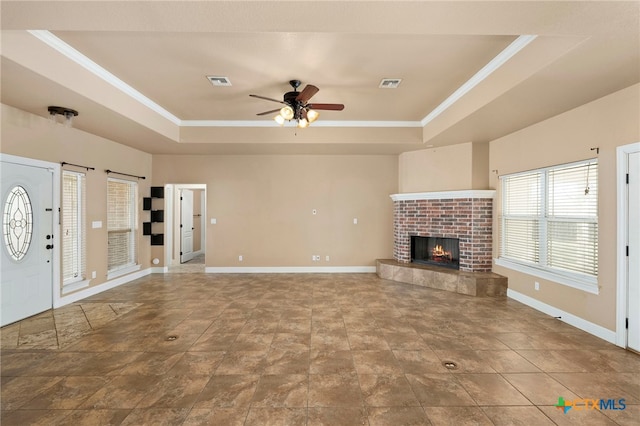 unfurnished living room featuring a raised ceiling, crown molding, ceiling fan, and a fireplace