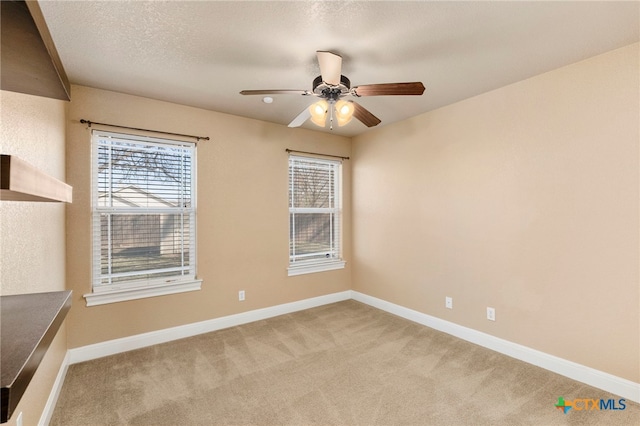 carpeted spare room featuring a textured ceiling and ceiling fan